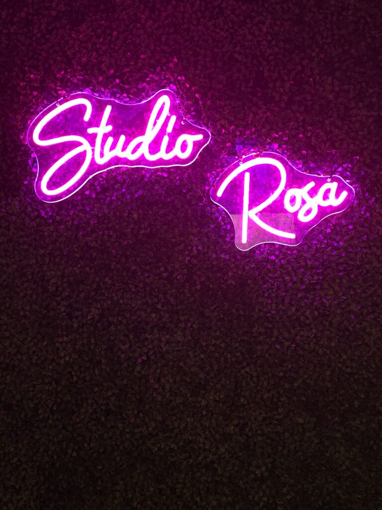 Roze neonletters Studio Rosa op een donkere wand in de salon in Hoevelaken