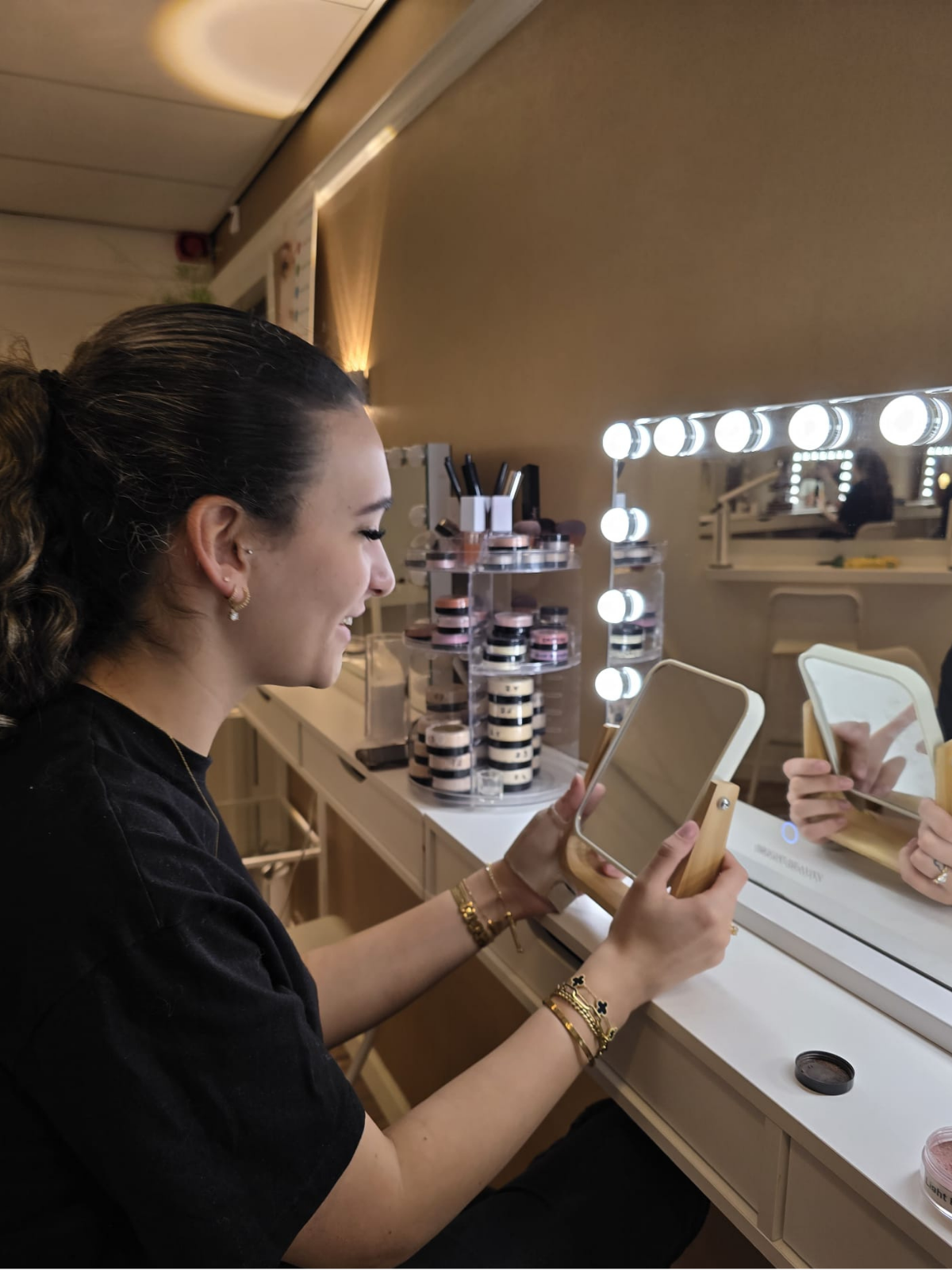 Een make-upspecialiste van Studio Rosa aan de verlichte make-upspiegel.