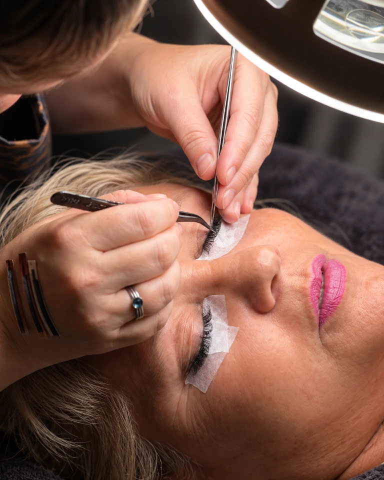 Wimperextensions worden met een pincet aangebracht bij Studio Rosa, onder een loeplamp