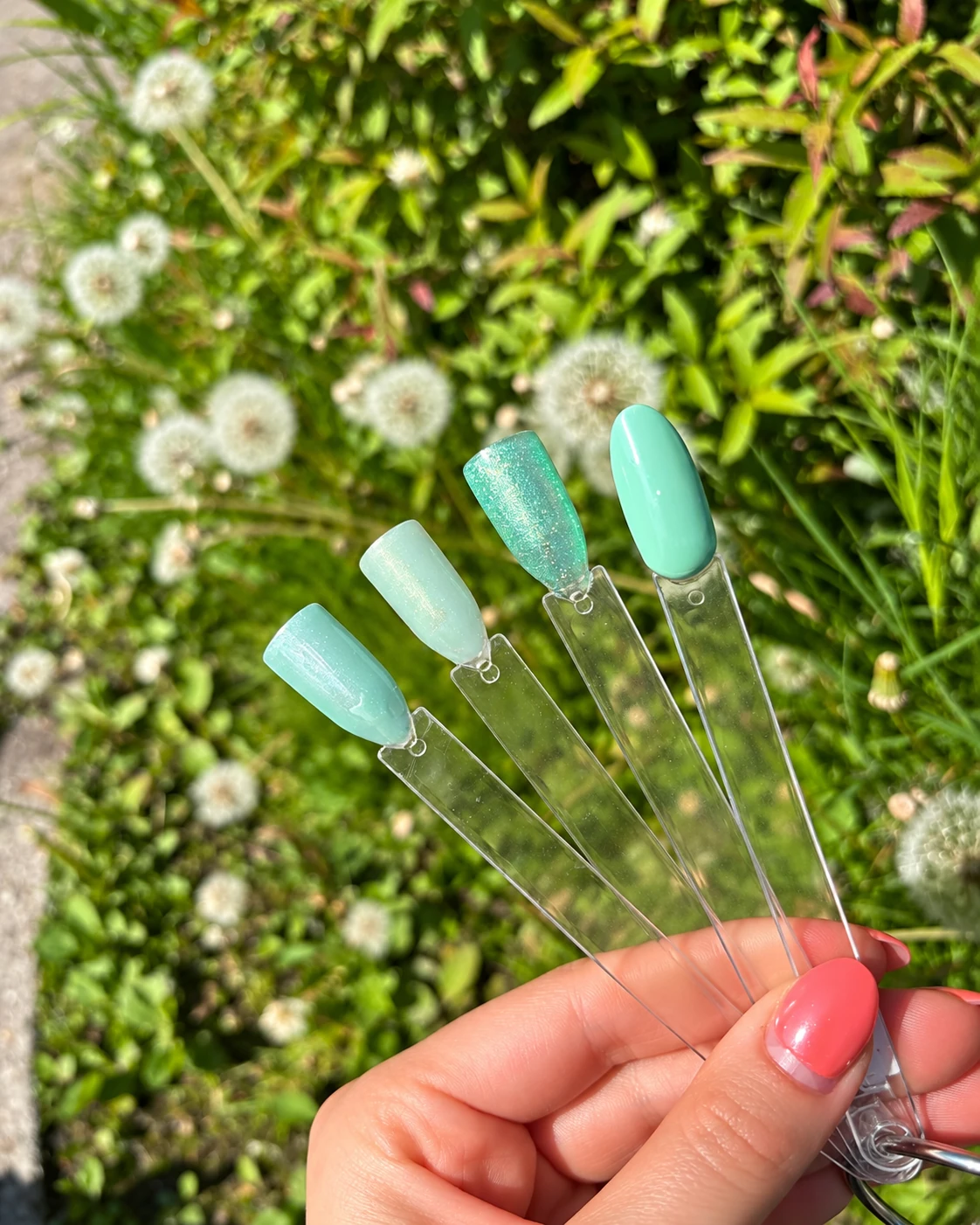 Nagelkleuren in mintgroen, vastgehouden tussen de bloemen